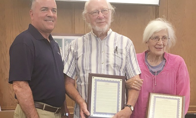 Keith Johnson receives an award from the Woodstock City Council with his wife, Nancy, next to him.
